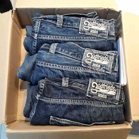 3 versleten jeans ter herstelling in een doos